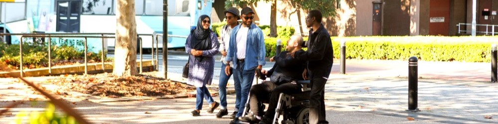 A group walking together outdoors, including a person using a wheelchair.