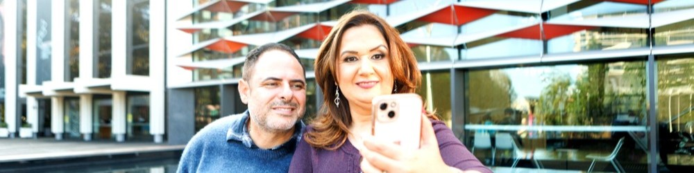 A couple taking a selfie in front of a modern building.