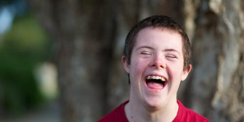 Close-up of a young man laughing outdoors.