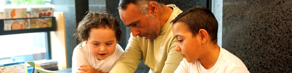 An adult and two young children reading a book together in a cozy setting.