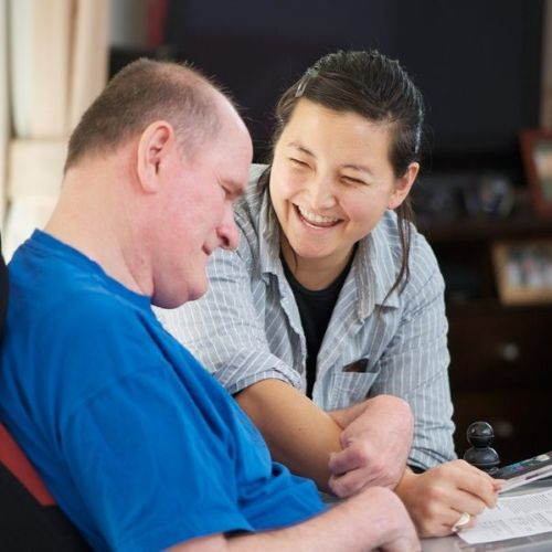 Staff Member smiling with a Man in an Electric Wheelchair