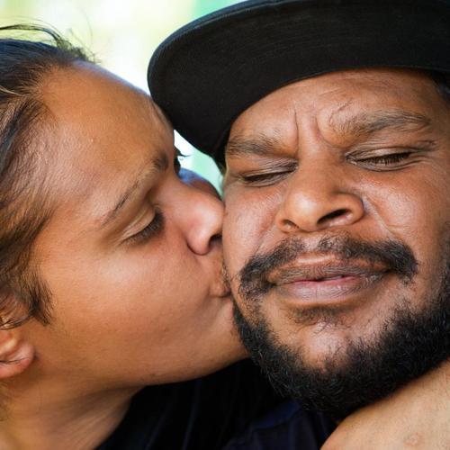 Close-up of a woman kissing a man on the cheek, showing affection.
