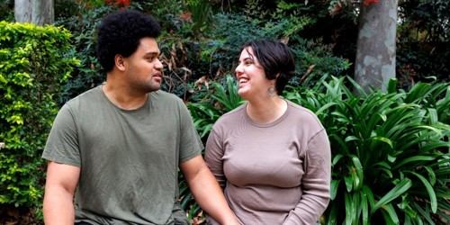 Two people sitting outdoors in a garden, smiling and talking together.
